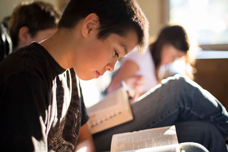 Boy reading scriptures with class